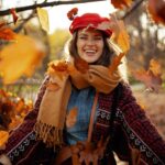 a woman smiling amongst fall leaves in a park