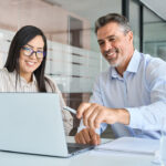 manager mentor teaching female worker looking at laptop discussing strategy