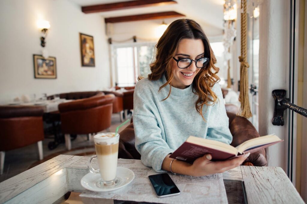 Smiling woman at coffee shop reading best productivity books
