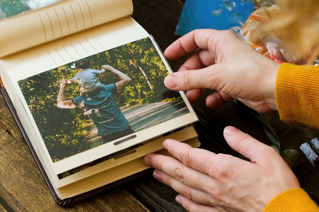 Young woman adding printed photo to family picture album