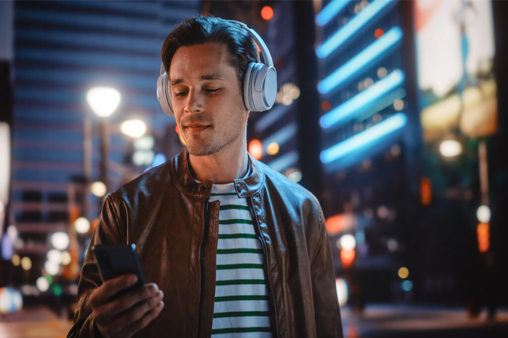 Man walking through city streets listening to an entertainment entrepreneur podcast