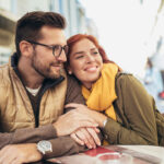 young couple in love sitting at the cafe table outdoors