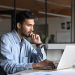 man working at laptop, sitting at workplace table