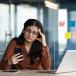 A worried business woman holding phone in her hands at the office
