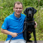man in blue shirt with guide dog