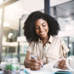 woman with notebook writing notes with pen in workplace