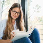 woman reading a book by the window