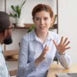 Two coworkers speaking to one another in the workplace