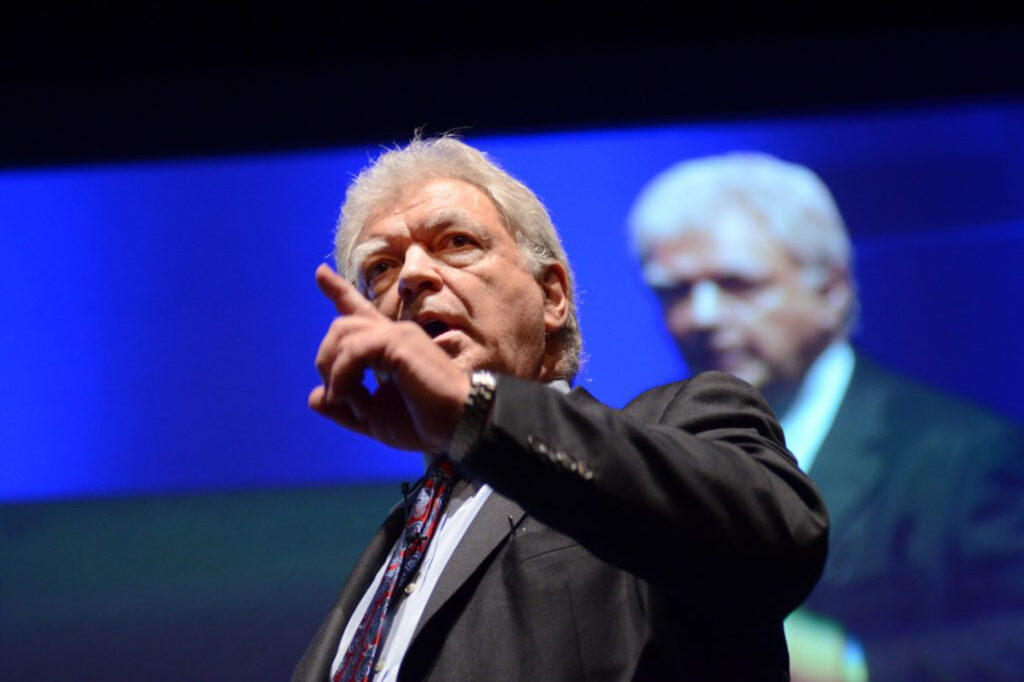 Leadership professor and former hostage negotiator George Kohlrieser speaks on stage at an event, teaching audiences how to negotiate