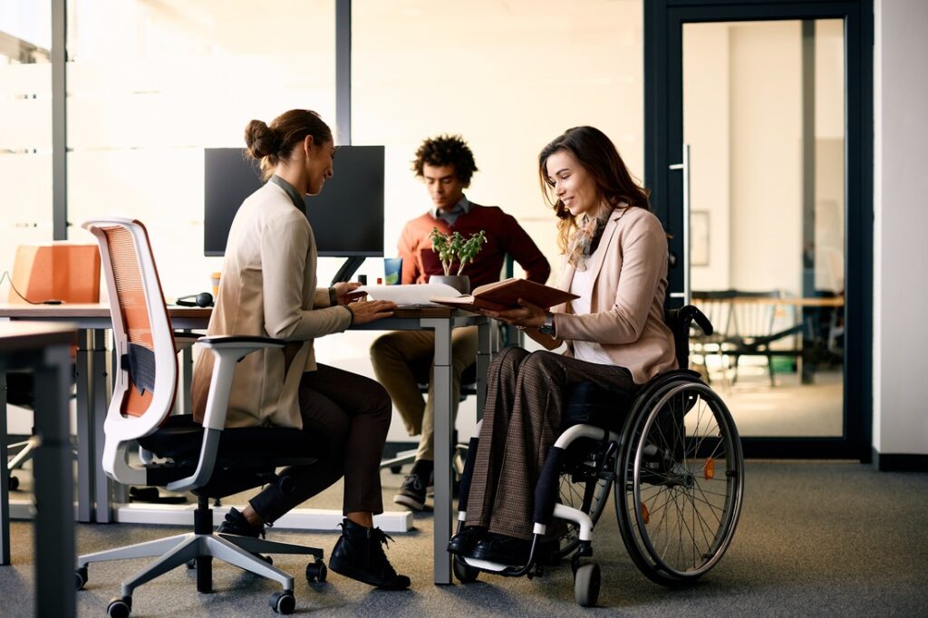 A woman in a wheelchair collaborates with other coworkers in an office space