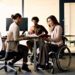 A woman in a wheelchair collaborates with other coworkers in an office space