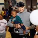Kyle Kuzma holding a toddler and smiling