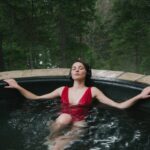 Woman listening to Myndstream on headphones in a hot tub in the woods