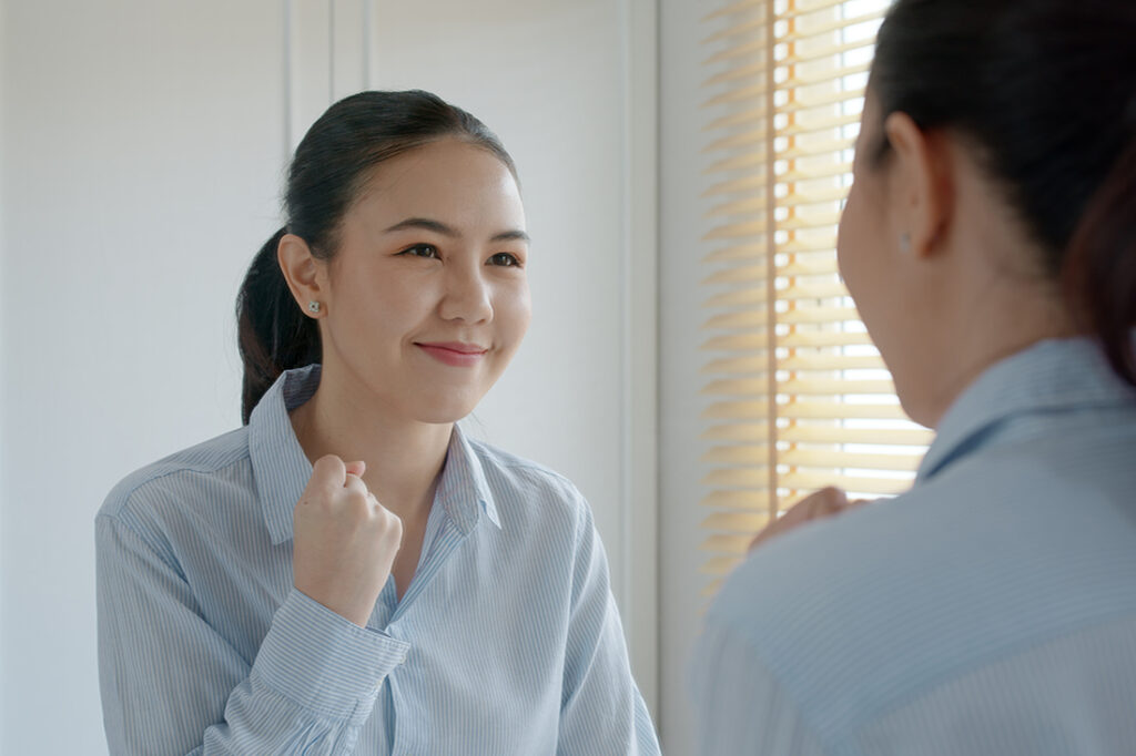 A woman encourages herself in the mirror on her self-improvement journey