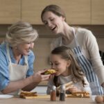 A woman making sandwiches with her mother and daughter.