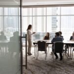 A wide shot of a woman giving a presentation in a conference room.