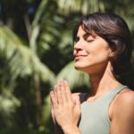 a woman holding her hands in a yoga pose while outside in nature