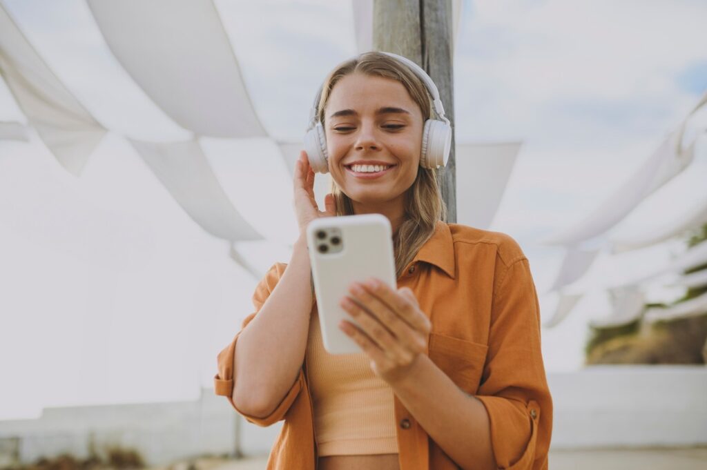 a woman wearing headphones and holding a smartphone while listening to an audiobook