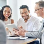 team members sitting at an office table and smiling during a team meeting