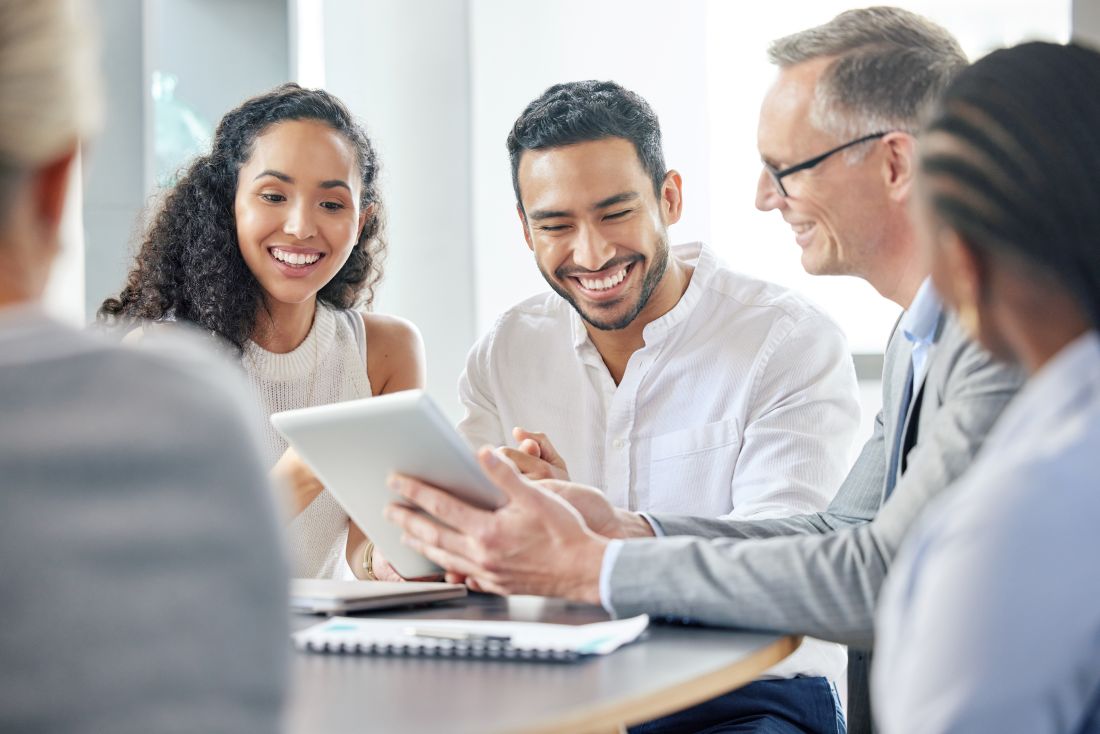 team members sitting at an office table and smiling during a team meeting
