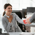 A woman happily accepting a gift from a colleague at work