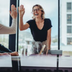 Businesswoman giving high five to colleague in meeting