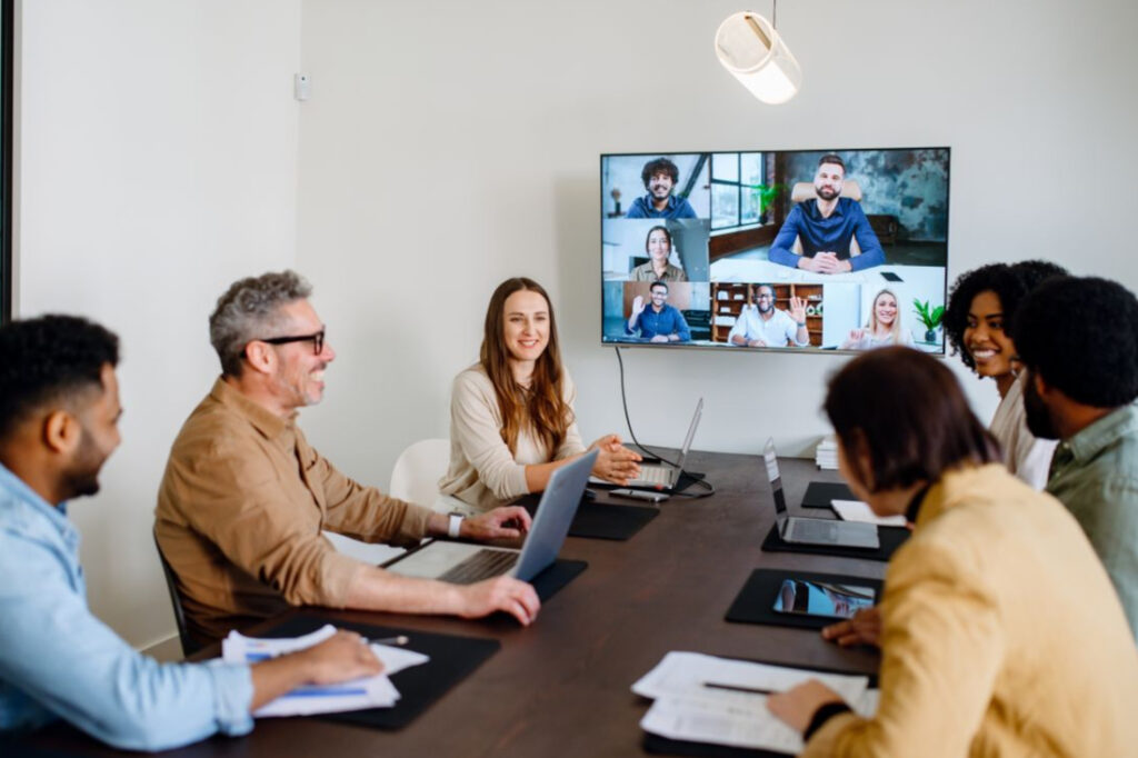 Employees having an in-person business meeting with some staff attending remotely