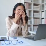 a woman looking stressed while sitting at her work desk